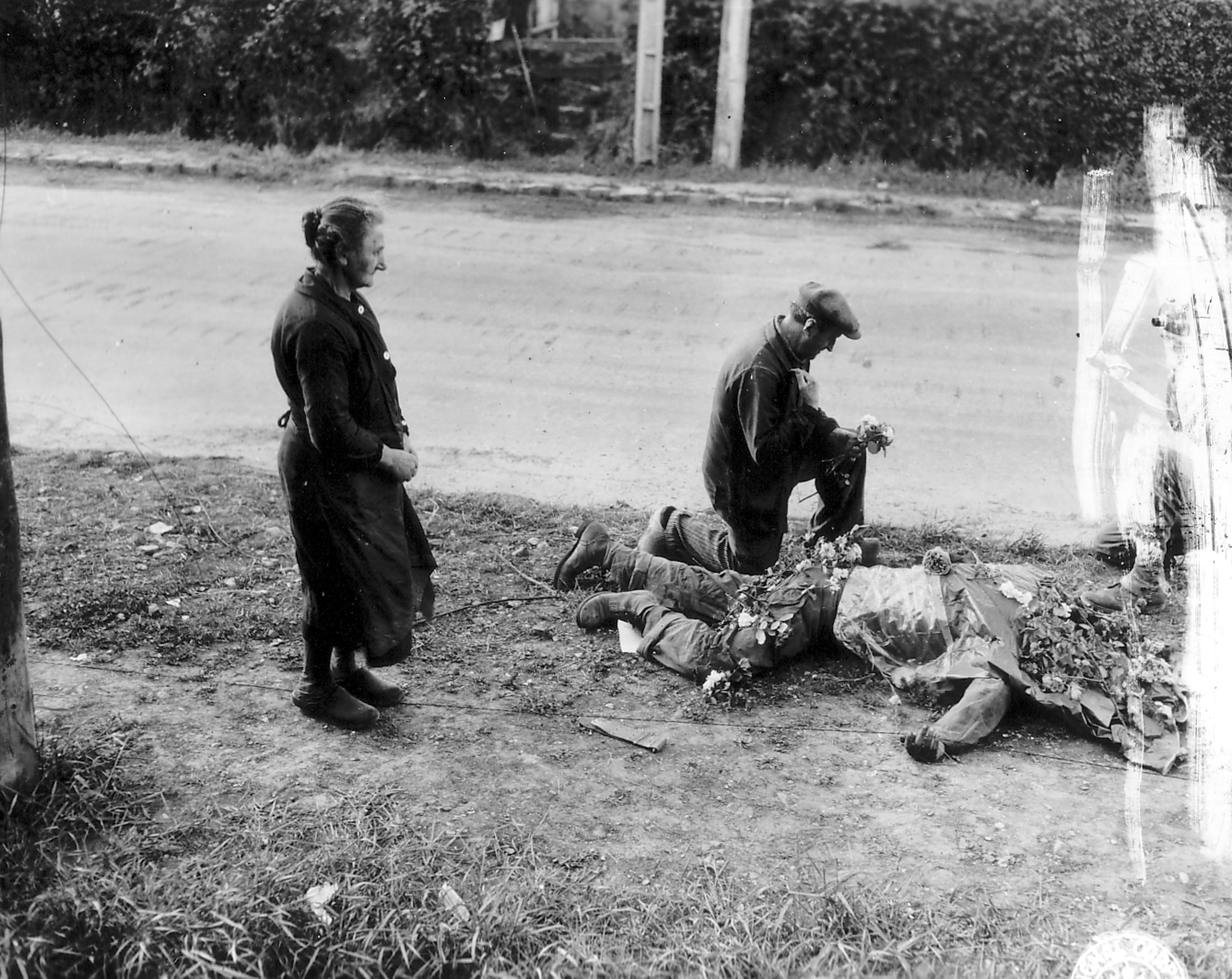 French civilians placing flowers on fallen American soldiers at Carentan, 1944
